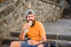 What are you eating today. Caucasian guy enjoy eating out. Bearded man eating unhealthy hotdog sandwich. Hipster eating royalty free stock photography What are you eating today. Caucasian guy enjoy eating out. Bearded man eating unhealthy hotdog sandwich. Hipster eating royalty free stock photography