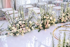 The white carpet for the wedding ceremony is decorated with flower compositions of roses, buttercup and bells with transparent cha royalty free stock photo The white carpet for the wedding ceremony is decorated with flower compositions of roses, buttercup and bells with transparent cha royalty free stock photo