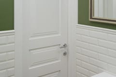 White door in the bathroom toilet room. Background green painted wall covered with decorative ceramic tiles with white glossy bric Royalty Free Stock Photos White door in the bathroom toilet room. Background green painted wall covered with decorative ceramic tiles with white glossy bric Royalty Free Stock Photos