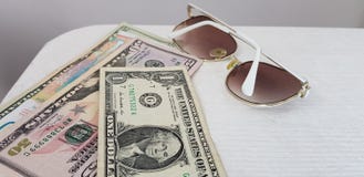 White fashionable sunglasses lay near american dollars paper bills stock images White fashionable sunglasses lay near american dollars paper bills stock images