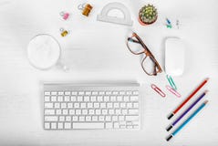 White office desk table with computer mouse and keyboard, cup of latte coffee, pencils and eye glasses. Top view with copy space, stock photo White office desk table with computer mouse and keyboard, cup of latte coffee, pencils and eye glasses. Top view with copy space, stock photo