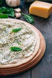 White pizza dough ready to bake on a round wooden board. Different infredients cheese basil leaves garlic on a wooden background. stock photography White pizza dough ready to bake on a round wooden board. Different infredients cheese basil leaves garlic on a wooden background. stock photography