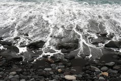 White surf breaking on a black sand beach with colored pebbles and stones in puerto de la cruz tenerife stock photo White surf breaking on a black sand beach with colored pebbles and stones in puerto de la cruz tenerife stock photo