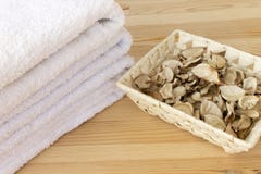 White towels and basket with spicy dry plants on a light wooden background stock photography White towels and basket with spicy dry plants on a light wooden background stock photography