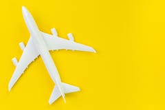White toy commercial airplane on solid yellow background using as travel and transportation business wallpaper