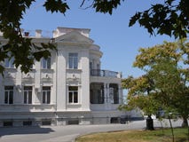 A white two-story mansion, an estate with stucco molding, a balcony, trees and a lawn against the background of a hollow royalty free stock photos A white two-story mansion, an estate with stucco molding, a balcony, trees and a lawn against the background of a hollow royalty free stock photos