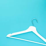 White wooden hangers on blue background stock photos White wooden hangers on blue background stock photos