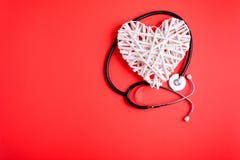 White Wooden Heart With Black Stethoscope On Red Paper Background. Heart Health Concept. Stock Photography