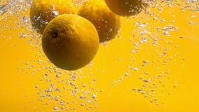 Whole oranges falling into water iin slow motion