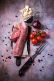 Whole pork tenderloin meat on vintage board with garlic and tomatoes Stock Photos Whole pork tenderloin meat on vintage board with garlic and tomatoes Stock Photos