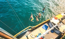 Widok z lotu ptaka szczęśliwi millenial przyjaciele skacze od żaglówki na dennej ocean wycieczce wpólnie - Bogaci faceci i dziewc zdjęcie royalty free Widok z lotu ptaka szczęśliwi millenial przyjaciele skacze od żaglówki na dennej ocean wycieczce wpólnie - Bogaci faceci i dziewc zdjęcie royalty free