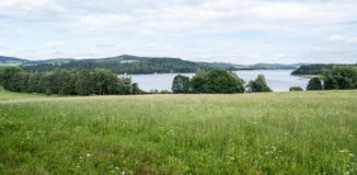 Wiese mit Wasserreservoir und Hügeln Lipno auf dem Hintergrund lizenzfreie stockfotos Wiese mit Wasserreservoir und Hügeln Lipno auf dem Hintergrund lizenzfreie stockfotos