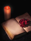 A wilted red rose, shot close-up, lies on the pages of an open book, next to a candle burns. blank page, space for text royalty free stock images A wilted red rose, shot close-up, lies on the pages of an open book, next to a candle burns. blank page, space for text royalty free stock images