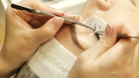 Wimperuitbreidingen in een schoonheidssalon op een model die kunstmatige wimpers met behulp van stock footage Wimperuitbreidingen in een schoonheidssalon op een model die kunstmatige wimpers met behulp van stock footage