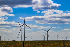 Wind turbine on Oklahoma prarie behind barbed wire fence - selective focus - under blue cloudy sky stock images Wind turbine on Oklahoma prarie behind barbed wire fence - selective focus - under blue cloudy sky stock images