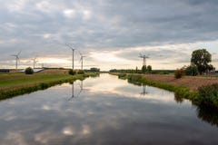 Wind turbines and high voltage pylons reflected in the water stock images Wind turbines and high voltage pylons reflected in the water stock images
