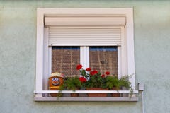 Window. Flowers on the window. Face of pumpkin on a windowsill. A window with shutters. The window of a private house. stock image Window. Flowers on the window. Face of pumpkin on a windowsill. A window with shutters. The window of a private house. stock image