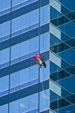 Window Washer In Orange Shirt On Blue Building Stock Images