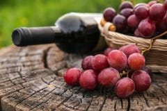 Wine bottle and basket with grapes on old wooden background stock photos Wine bottle and basket with grapes on old wooden background stock photos
