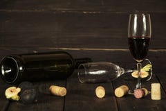 Wine in a glass an empty bottle of figs on a dark wooden background. A glass of wine on a wooden table. stock photo Wine in a glass an empty bottle of figs on a dark wooden background. A glass of wine on a wooden table. stock photo
