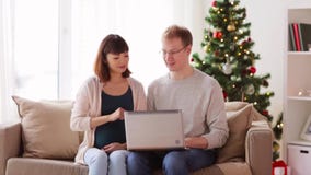 Man and pregnant wife with laptop at christmas