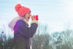 Winter outdoor portrait of young girl screaming in a megaphone paper cup, copy space royalty free stock image Winter outdoor portrait of young girl screaming in a megaphone paper cup, copy space royalty free stock image