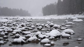 Winter scene on mountain river during heavy snowfall.