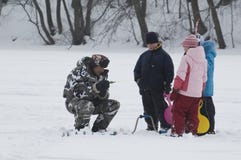 Winterfischen. Alter Fischer und junge Zuschauer Stockbild Winterfischen. Alter Fischer und junge Zuschauer Stockbild