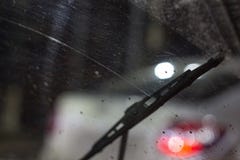 Wipers inside the car on a dirty scratched windshield, rain season, at night. the front and back backgrounds are blurred with stock photography Wipers inside the car on a dirty scratched windshield, rain season, at night. the front and back backgrounds are blurred with stock photography
