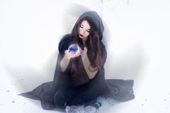 Witch Or Woman Doing Magic In Black Cloak With Glass Ball In White Snow Forest Stock Photography