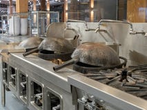 Woks έτοιμο να μαγειρεψει στην αναμμένη βιομηχανική κουζίνα στοκ φωτογραφία Woks έτοιμο να μαγειρεψει στην αναμμένη βιομηχανική κουζίνα στοκ φωτογραφία