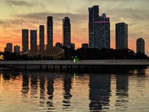 Wolkenkratzer nahe dem Wasser gegen die untergehende Sonne stockbild Wolkenkratzer nahe dem Wasser gegen die untergehende Sonne stockbild