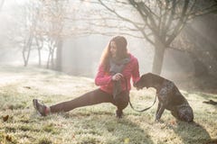 Woman And Her Dog Stretching Outdoor. Fitness Girl And Her Pet Working Out Together. Royalty Free Stock Images