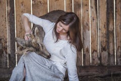 Woman with a baby deer in a pen is caring and take care
