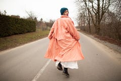 A woman in a beautiful coat and white dress rides along the way. Back viev royalty free stock photo A woman in a beautiful coat and white dress rides along the way. Back viev royalty free stock photo