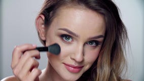 Woman with beauty face applying makeup blush with brush
