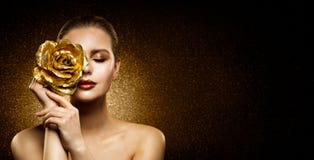 Woman Beauty Perfect glowing Skin Makeup. Fashion Model holding Golden Rose Flower over Face and covering Closed Eye. Artistic