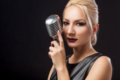 Woman in black leather dress holds a metal microphone stock image Woman in black leather dress holds a metal microphone stock image