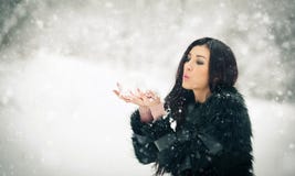 Woman Blowing Snow From Her Hands Enjoying The Winter. Happy Brunette Girl Playing With Snow In The Winter Landscape Stock Image