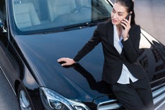 Young attractive woman in suit sitting on hood of passenger car and talking stock images Young attractive woman in suit sitting on hood of passenger car and talking stock images