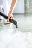Woman cleaning drain in bathroom with steam