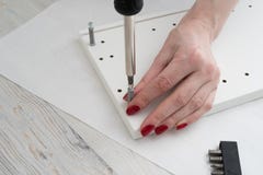 The woman collects the furniture, bought in disassembled condition according to the instruction, attached to the purchase stock photo The woman collects the furniture, bought in disassembled condition according to the instruction, attached to the purchase stock photo