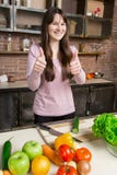 A woman cuts a cucumber in the kitchen with a knife. Preparation of salad.Brunette shows thumb stock images A woman cuts a cucumber in the kitchen with a knife. Preparation of salad.Brunette shows thumb stock images