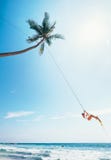 Woman dangles on tropical palm tree swing over ocean waves Royalty Free Stock Photography Woman dangles on tropical palm tree swing over ocean waves Royalty Free Stock Photography