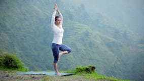 Woman doing yoga asana tree pose outdoors