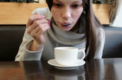 Woman drinks hot tea from cup with a spoon. Close up hands and face. royalty free stock images Woman drinks hot tea from cup with a spoon. Close up hands and face. royalty free stock images