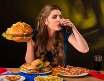 Woman eating french fries and hamburger on table. royalty free stock images Woman eating french fries and hamburger on table. royalty free stock images