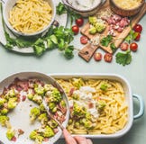 Woman female hands cooking pasta casserole with roasted romanesco cabbage and ham in creamy sauce on kitchen table background with stock photography Woman female hands cooking pasta casserole with roasted romanesco cabbage and ham in creamy sauce on kitchen table background with stock photography