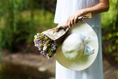 Woman with flowers and hat in hands. Close-up stock photography Woman with flowers and hat in hands. Close-up stock photography