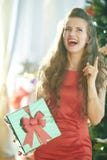 Woman with green Christmas gift got idea near Christmas tree stock photo Woman with green Christmas gift got idea near Christmas tree stock photo